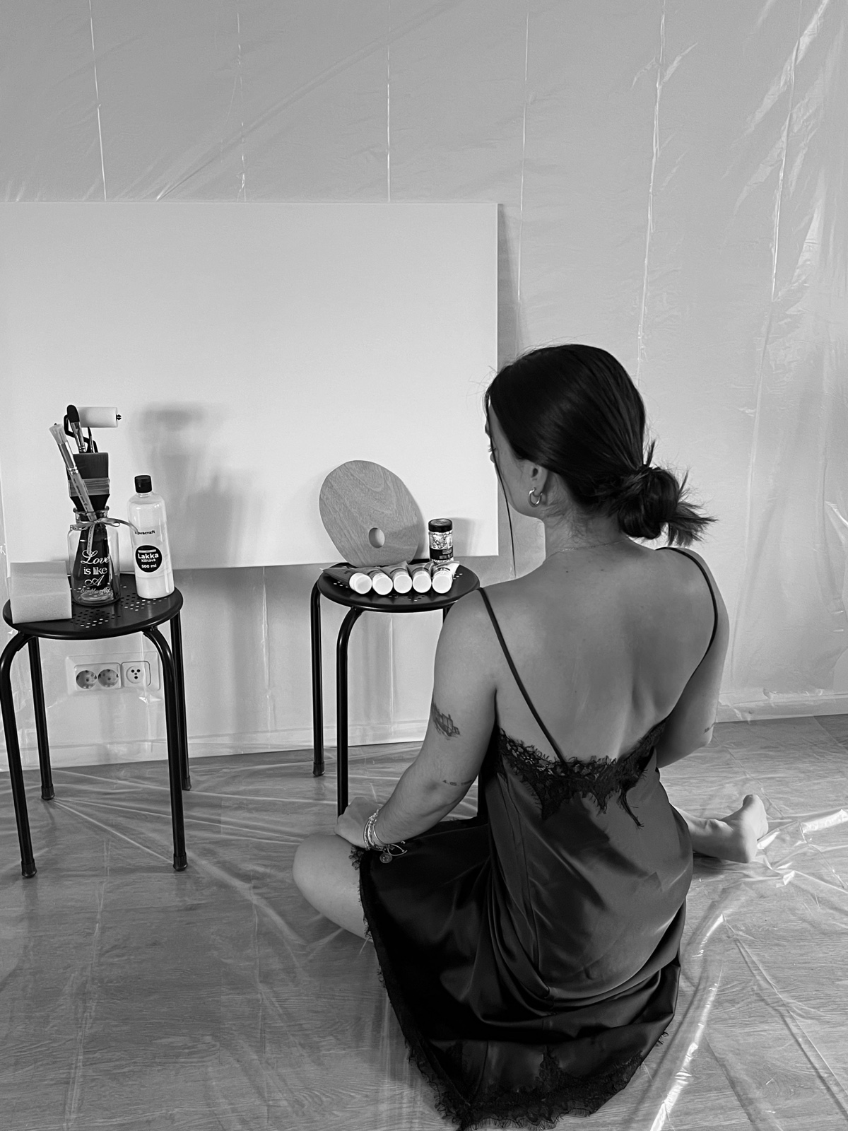 Saray Domeno Cardenas seated before a blank canvas with paints and brushes nearby
